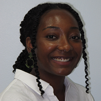 Smiling woman with braided hair wearing white shirt in professional headshot