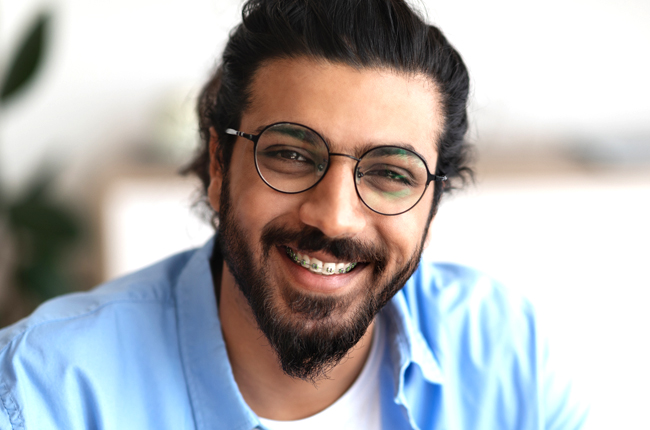 Smiling man wearing glasses and blue shirt in bright indoor setting