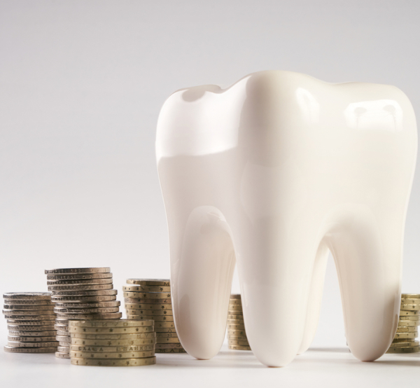 White tooth model surrounded by stacked coins representing dental investment costs.