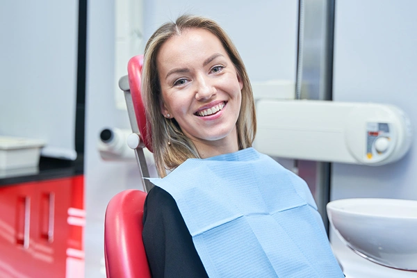 Woman in dental chair wearing blue bib, smiling at orthodontic office